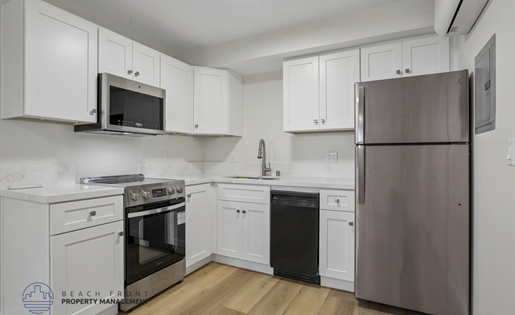 A kitchen with white cabinets and a stainless steel refrigerator.